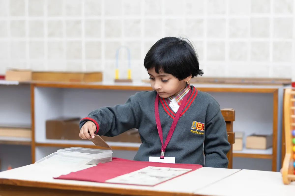 Child engaged in learning activity at a Montessori school, developing fine motor skills.