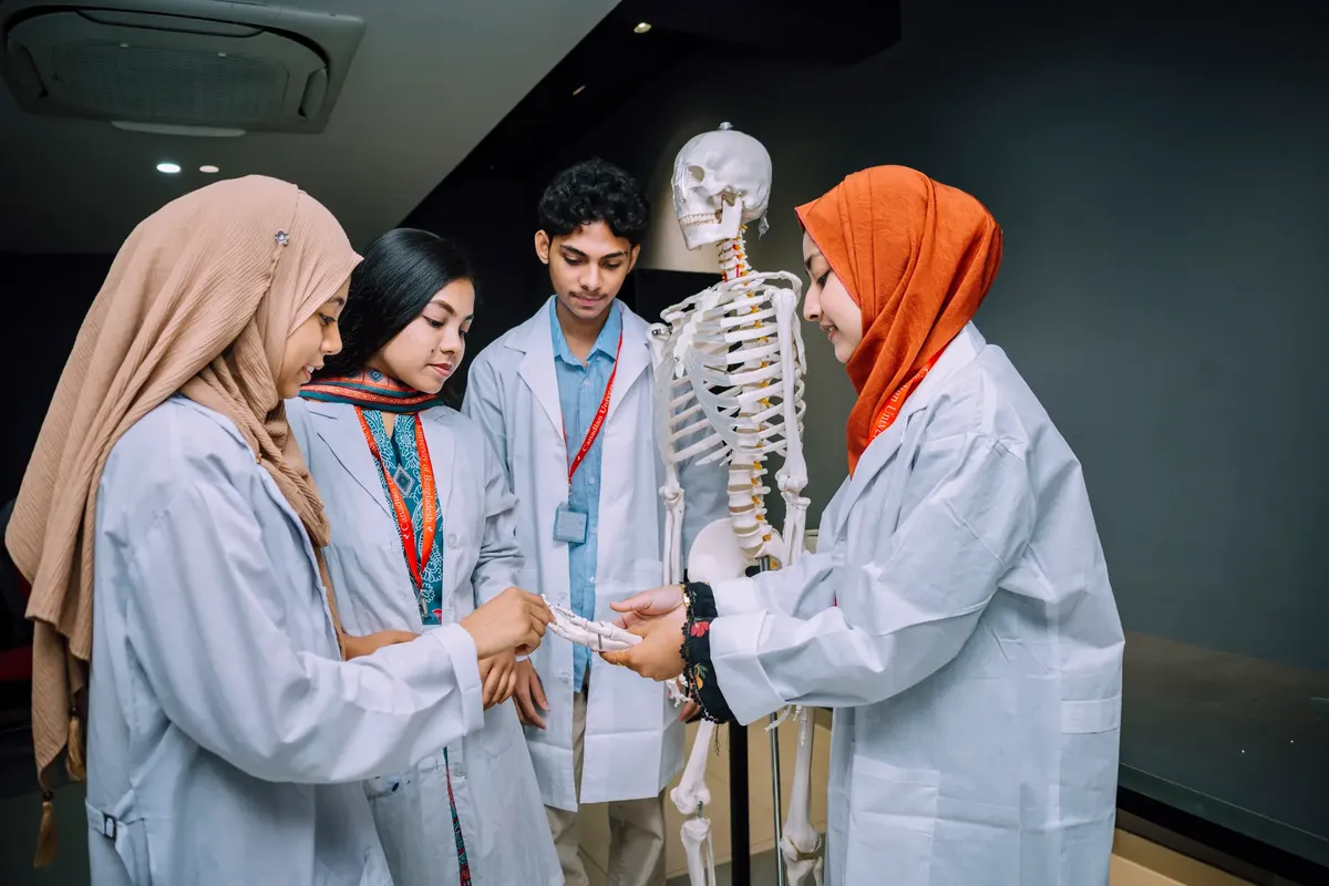 Group of South Asian medical students studying anatomy with a skeleton in a classroom setting.