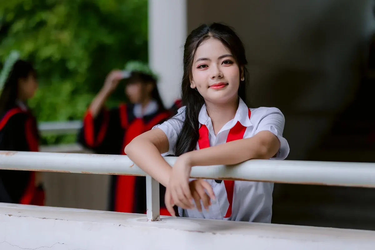 穿著校服的年輕女子在戶外畢業典禮中微笑 poses。